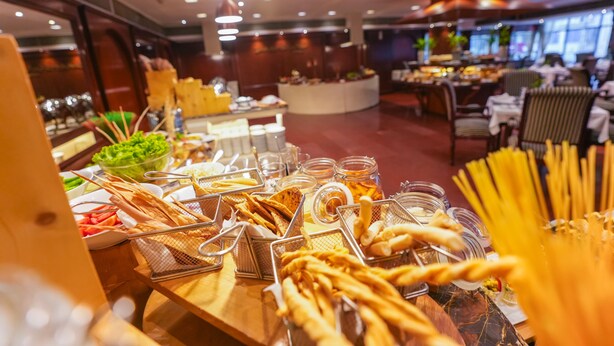 Disposición de bufé con diversos alimentos y una zona de estar al fondo.