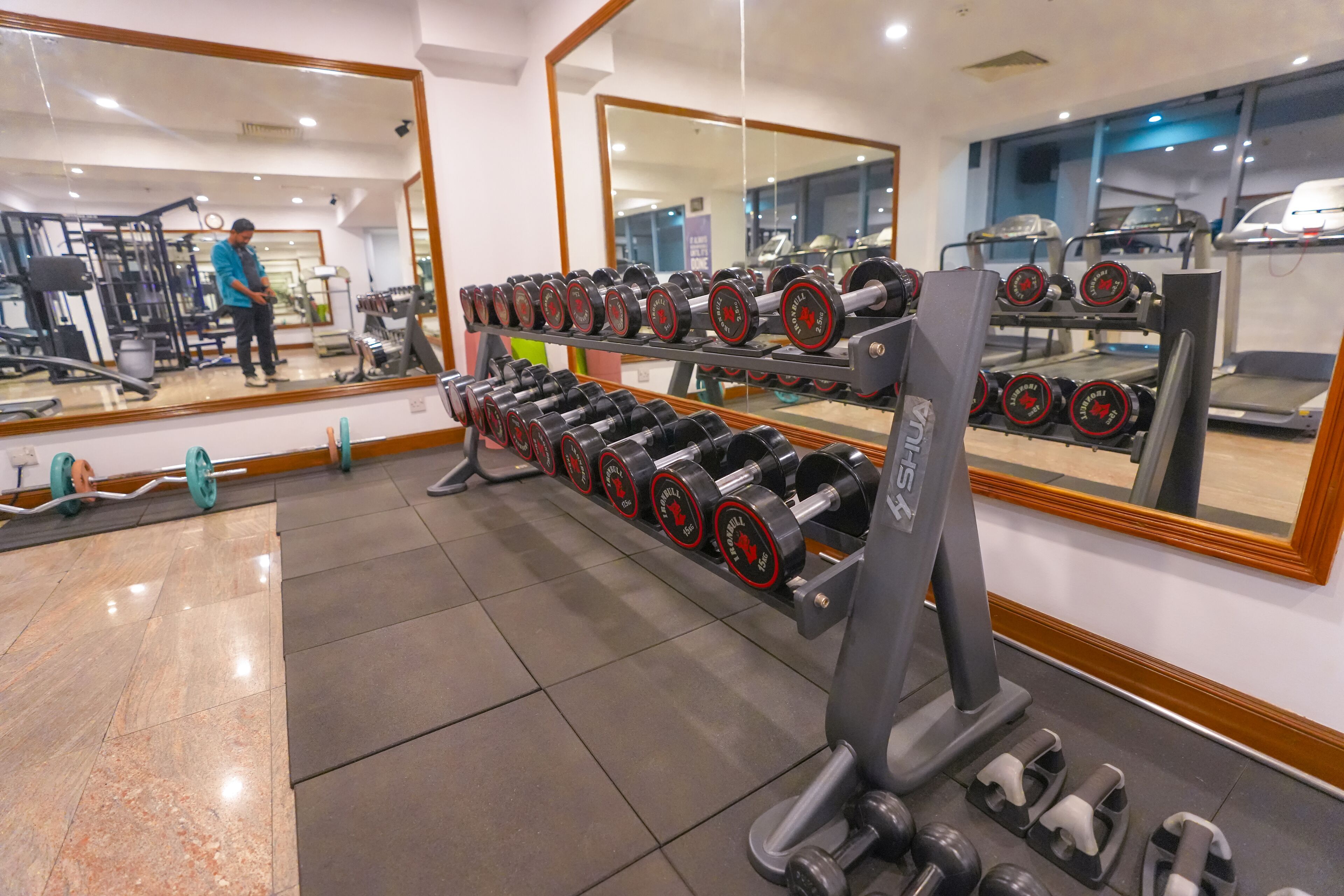 A gym with weightlifting equipment, mirrors, and exercise machines.