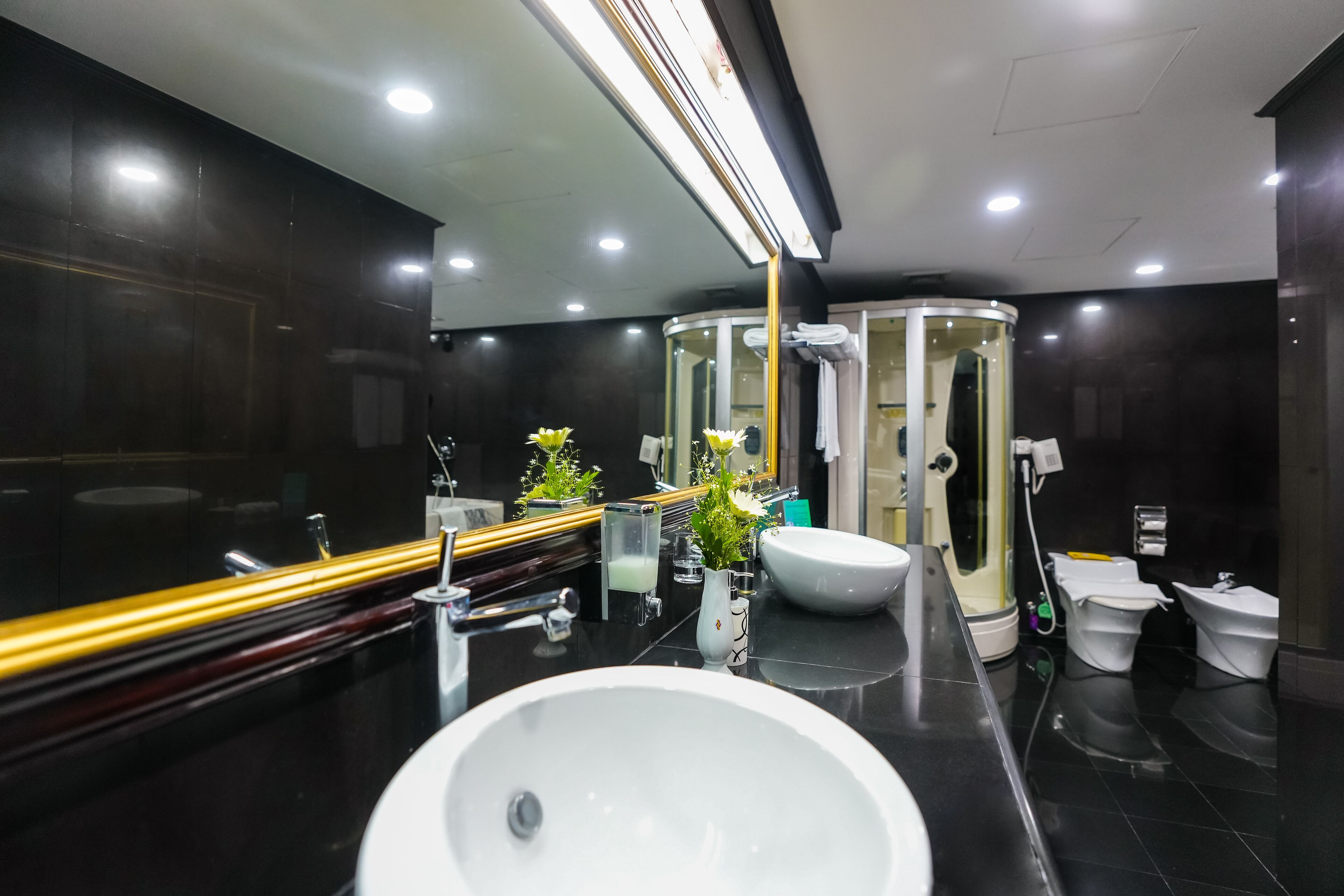 Un baño moderno con un lavamanos grande, un espejo y dos inodoros.