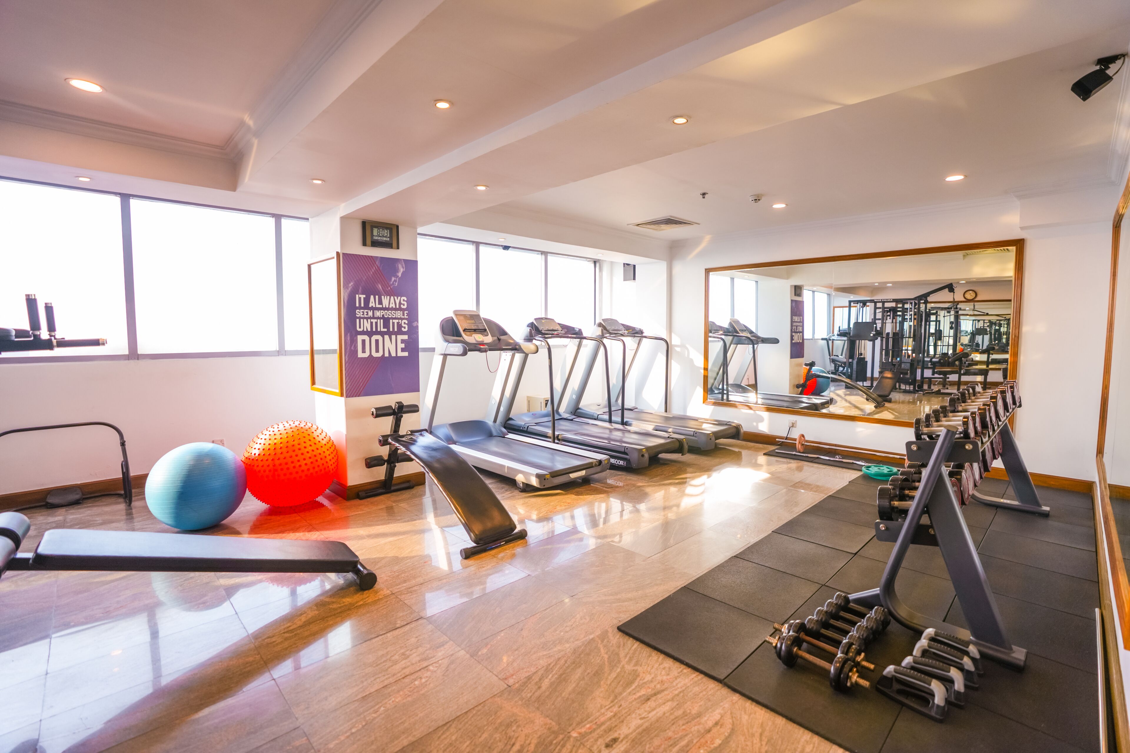 A gym with treadmills, exercise balls, and dumbbells.