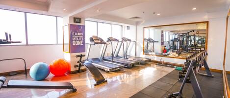 A gym with treadmills, exercise balls, and dumbbells.