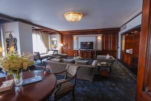 Habitación de hotel con sala de estar que incluye un sofá, un televisor y una araña.