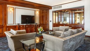 Un salón de hotel con televisor de pantalla plana, armarios de madera, un conjunto de sofás y un espejo grande.