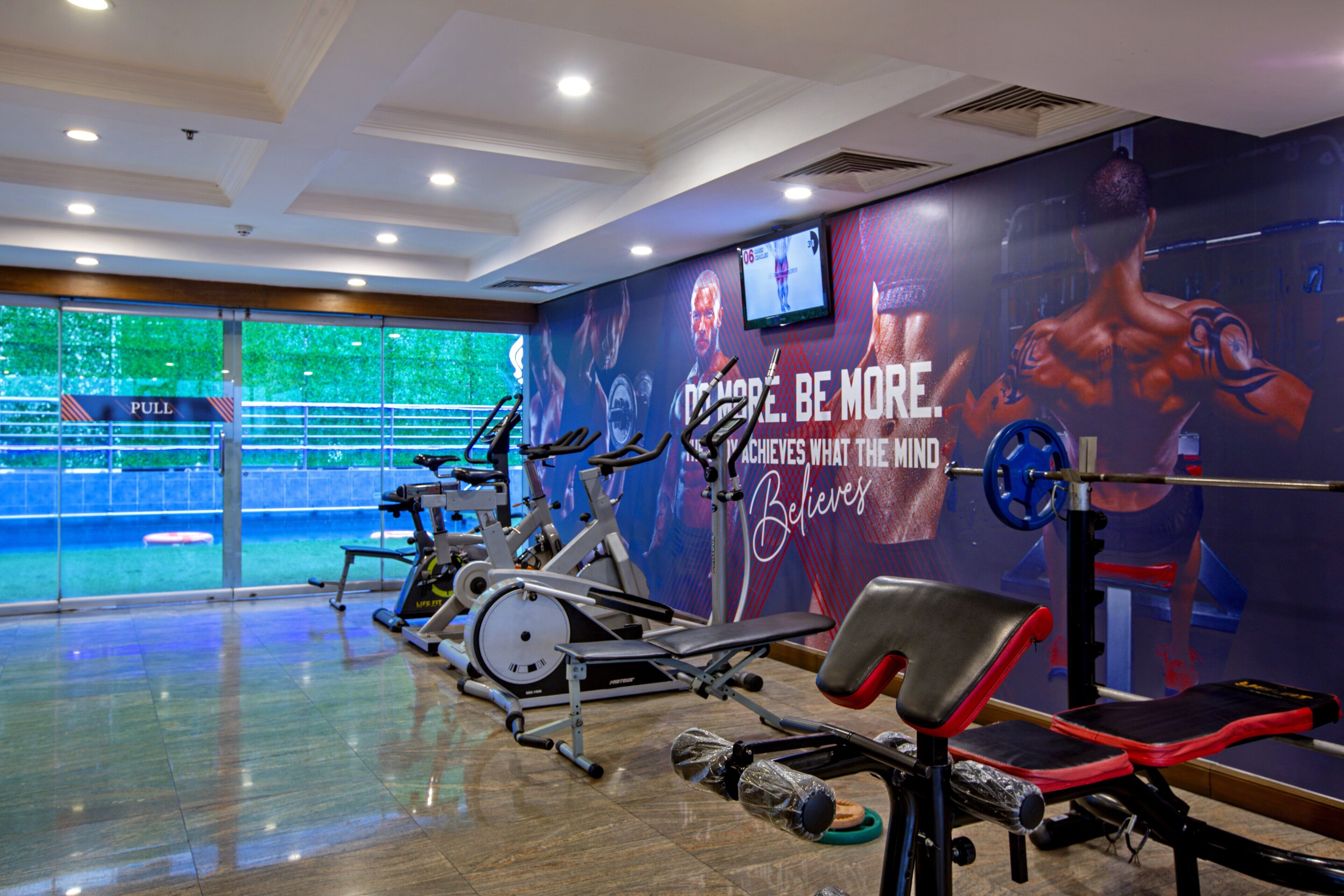 Ein Fitnessstudio mit Trainingsgeräten, einer Zugmaschine und einer Wand mit motivierenden Sprüchen und einem Fernsehbildschirm.
