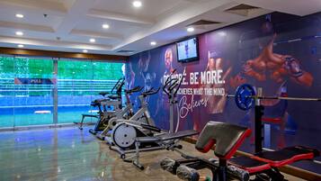 Ein Fitnessstudio mit Trainingsgeräten, einer Zugmaschine und einer Wand mit motivierenden Sprüchen und einem Fernsehbildschirm.