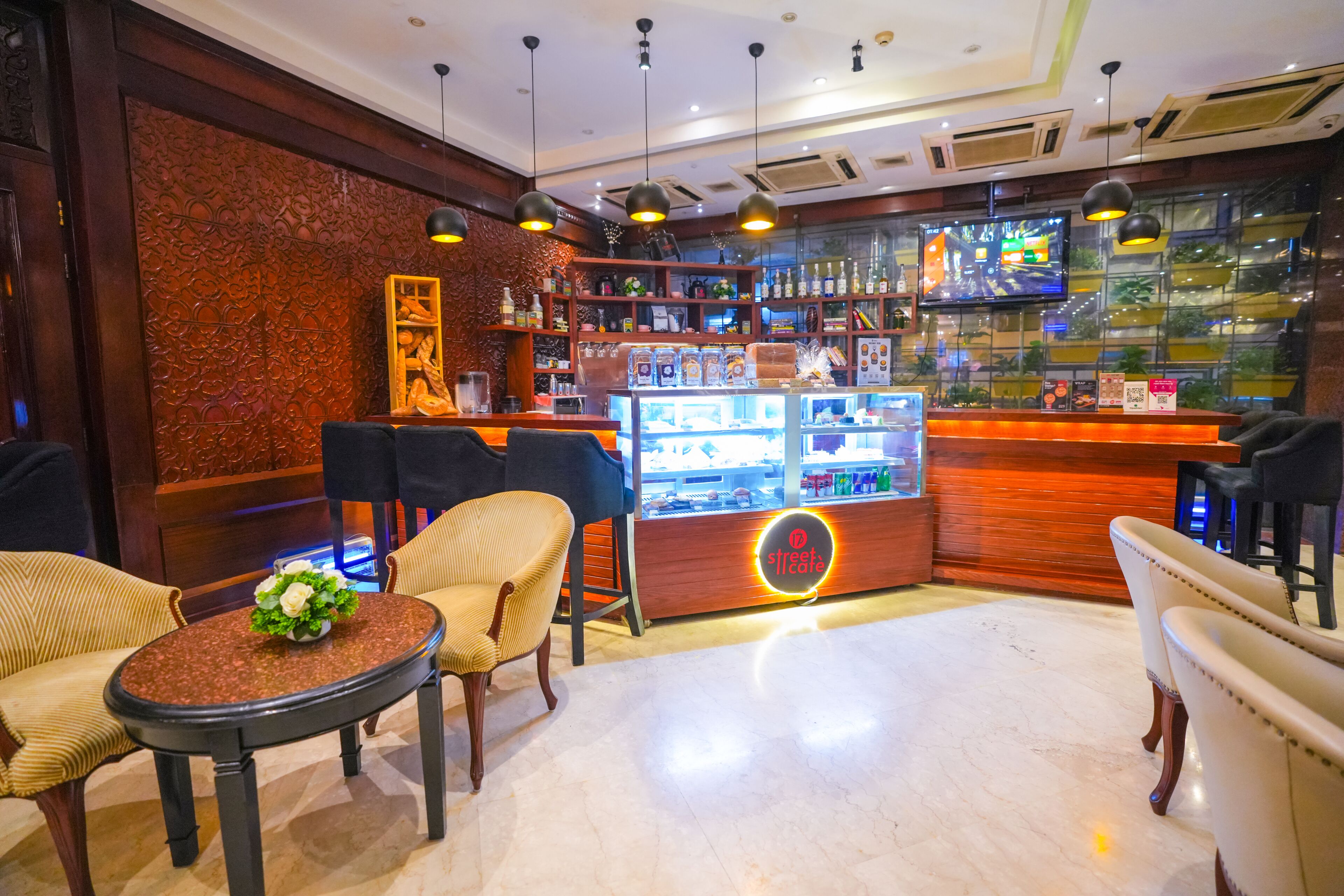 Un coin bar accueillant avec des sièges, un comptoir orné d’un néon et un téléviseur diffusant des images d’une ville.