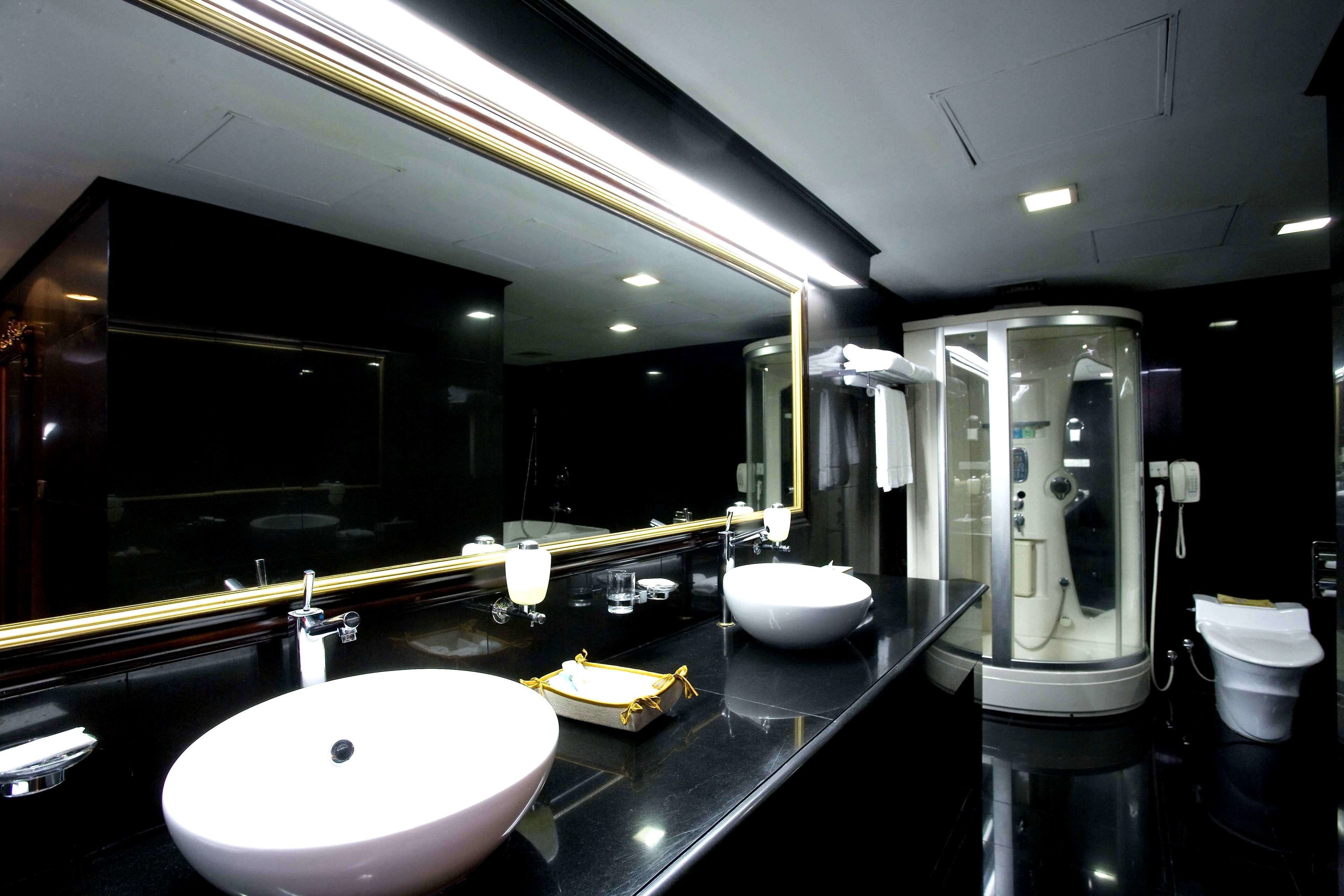 A modern bathroom with two sinks, a large mirror, and a walk-in shower.