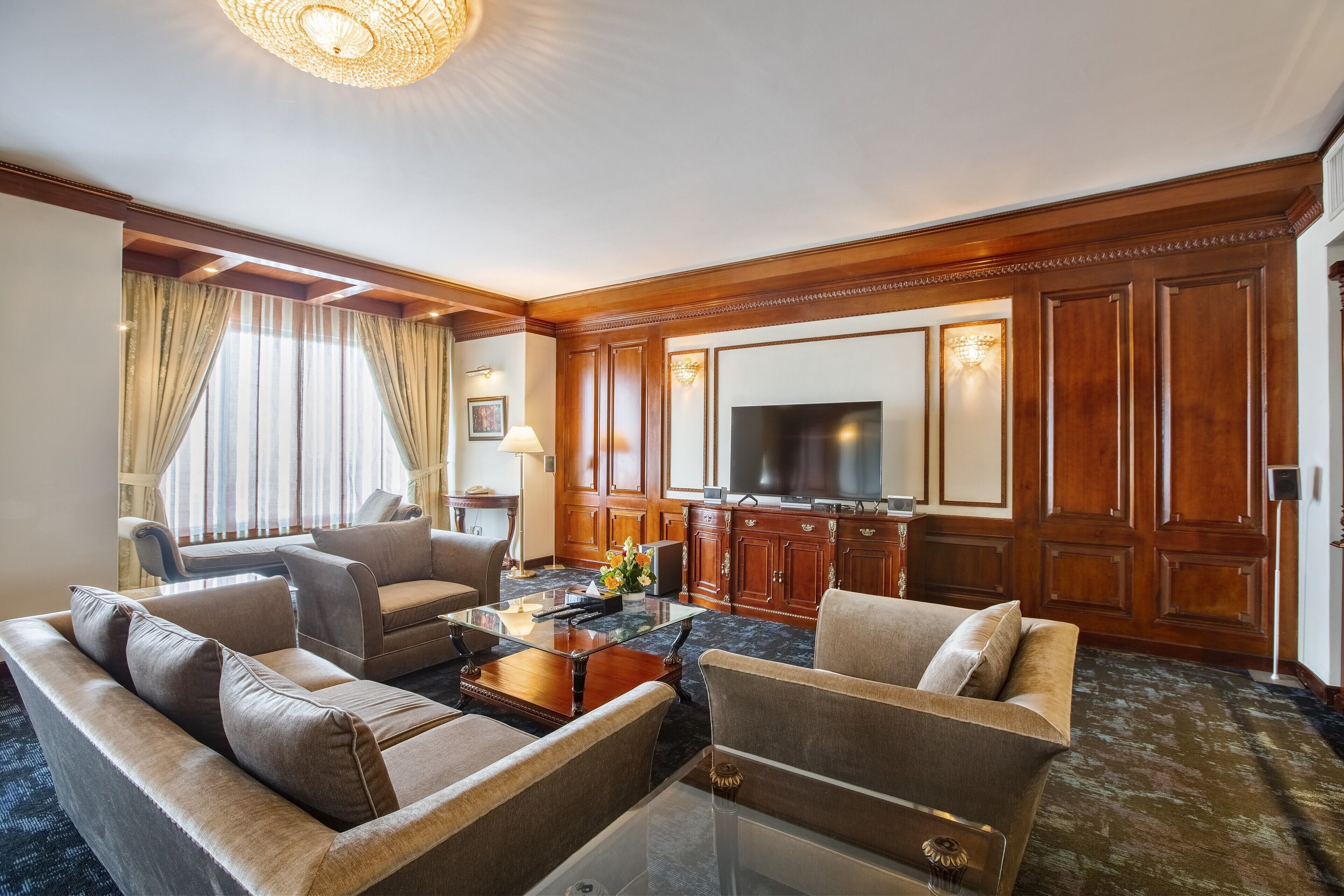 A spacious living room with a large flat-screen TV, comfortable seating, and wooden paneling.