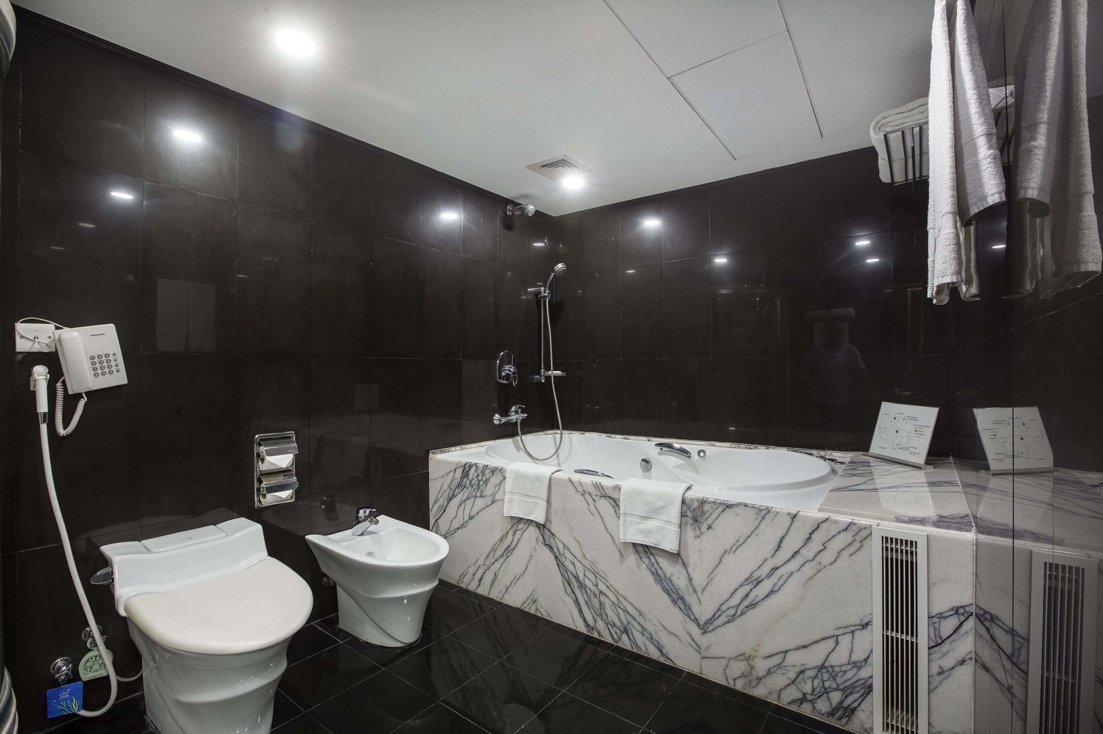 A modern bathroom with a large bathtub, a toilet, and a bidet.