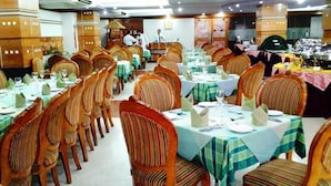 A banquet hall with rows of wooden chairs and tables set for a formal event. - Hotel Victory (Dhaka)