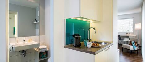 Un baño moderno con lavamanos, espejo y zona de ducha iluminada en verde.