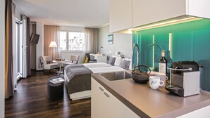 Una habitación de hotel moderna con cama, escritorio, silla, cafetera y ventana con cortinas.