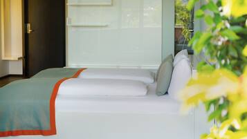 Ein modernes Zimmer mit Bett, Fenster und Pflanze.