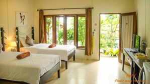 Quarto de hotel com duas camas, televisão, secretária e vista para o verde lá fora.