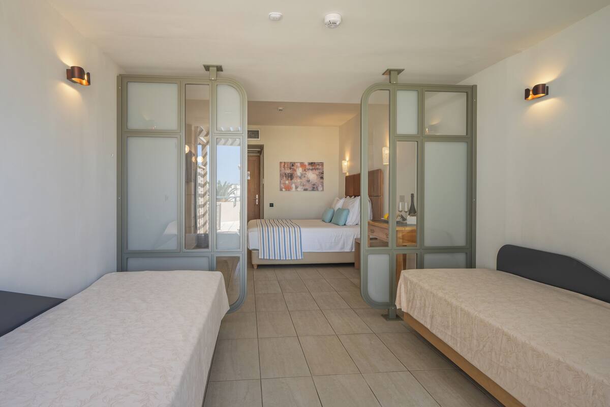 Une chambre d’hôtel avec deux lits simples, une grande fenêtre et un tableau au mur.