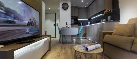 Ein modernes Wohnzimmer mit Fernseher, Sofa und Essbereich.