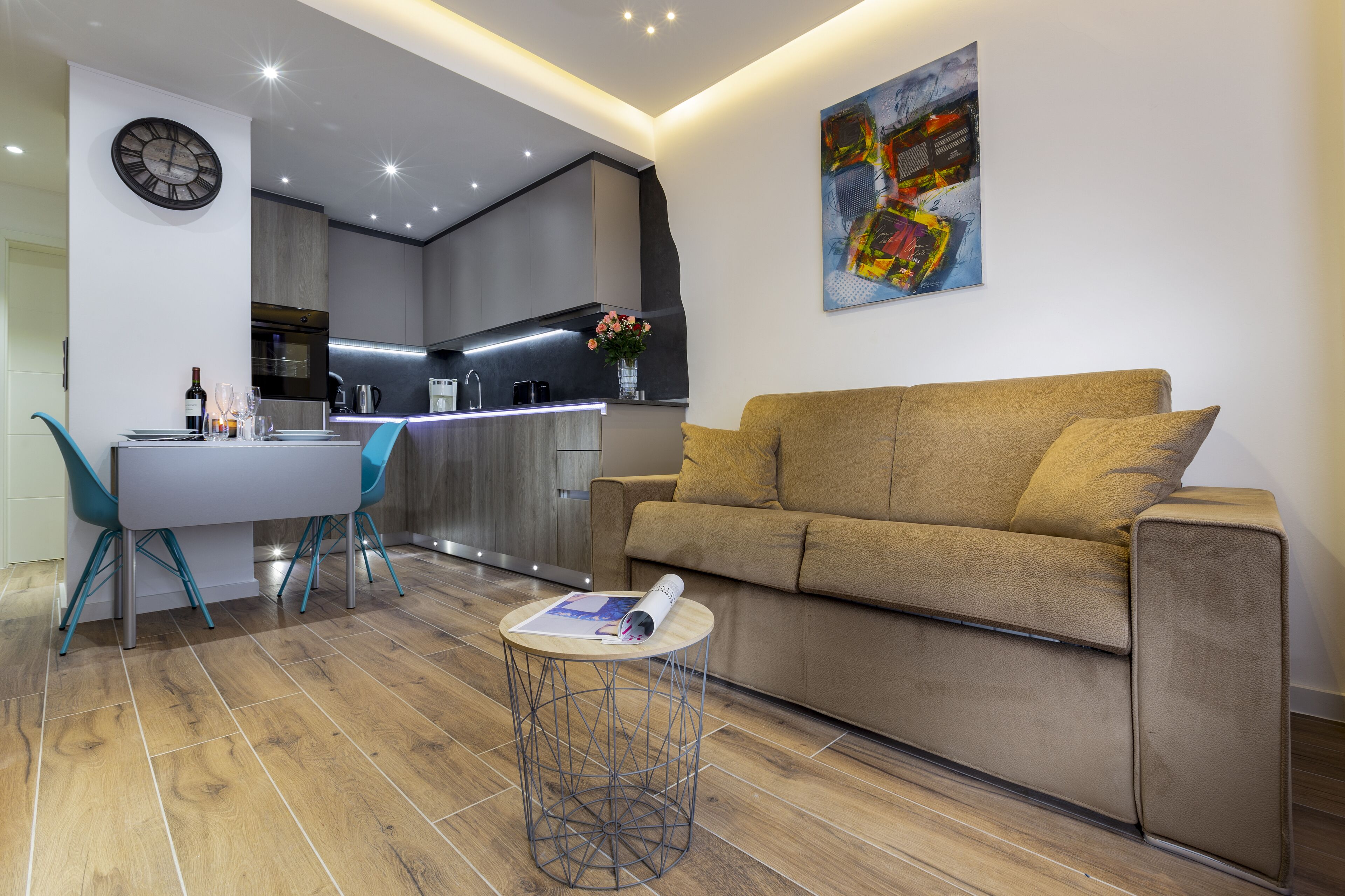A modern living room with a sofa, a dining table with chairs, and a small side table with a magazine.