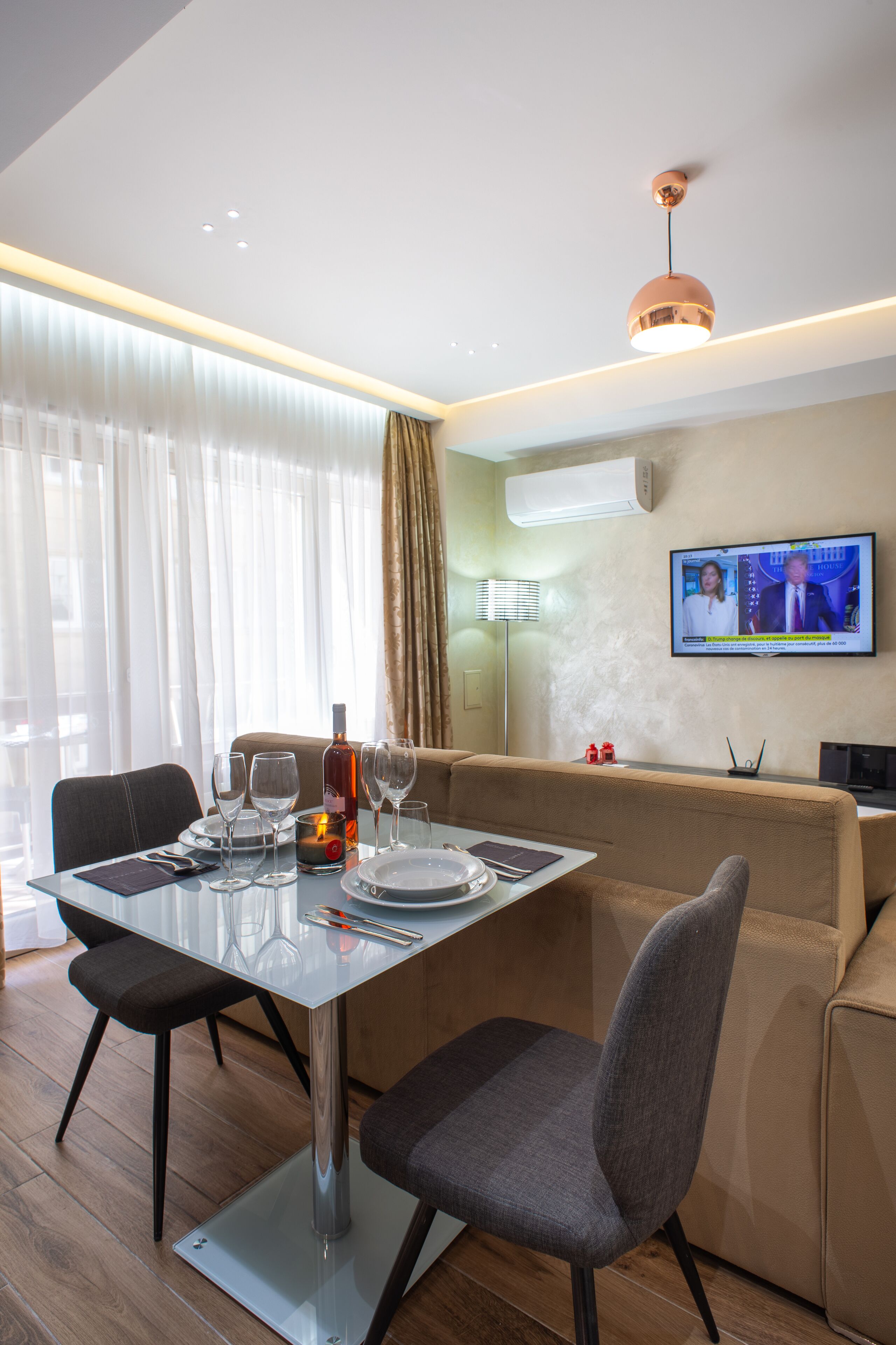 Un espace repas moderne avec une table en verre, des chaises et un téléviseur fixé au mur.