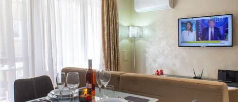 Un espace repas moderne avec une table en verre, des chaises et un téléviseur fixé au mur.