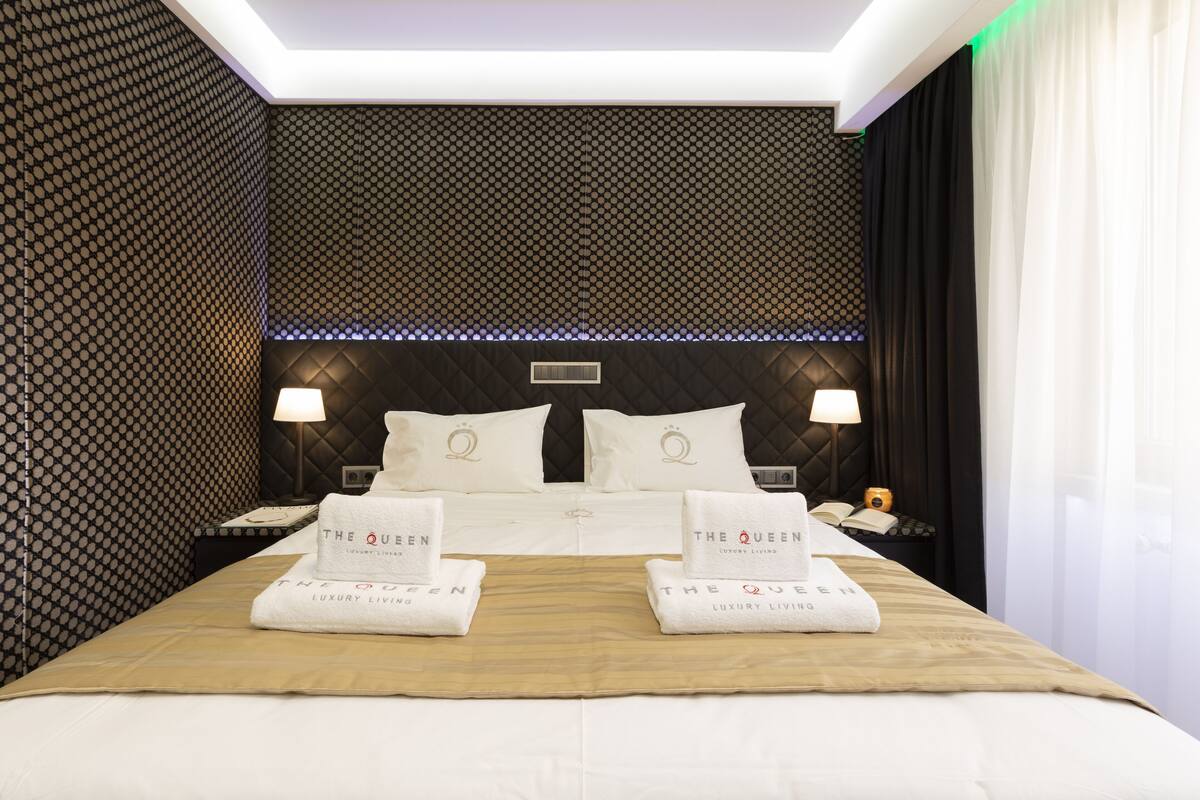 A hotel room with a large bed, two bedside tables, and a headboard with a geometric pattern.