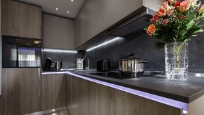 Una cocina moderna con horno empotrado, cafetera y un florero con flores sobre la encimera.