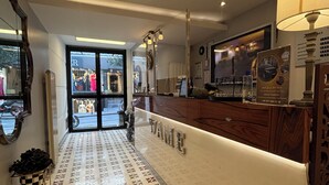 A hotel reception area with a patterned floor, a reception desk, and a view of the street outside. - Wame Suite Hotel (Istanbul)