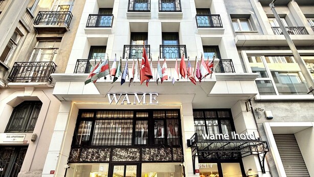 A hotel with a prominent 'WAME' sign, multiple balconies, and a variety of flags displayed outside. - Wame Suite Hotel (Istanbul)