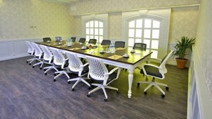 Un salón de conferencias con una larga mesa, sillas blancas y portátiles.
