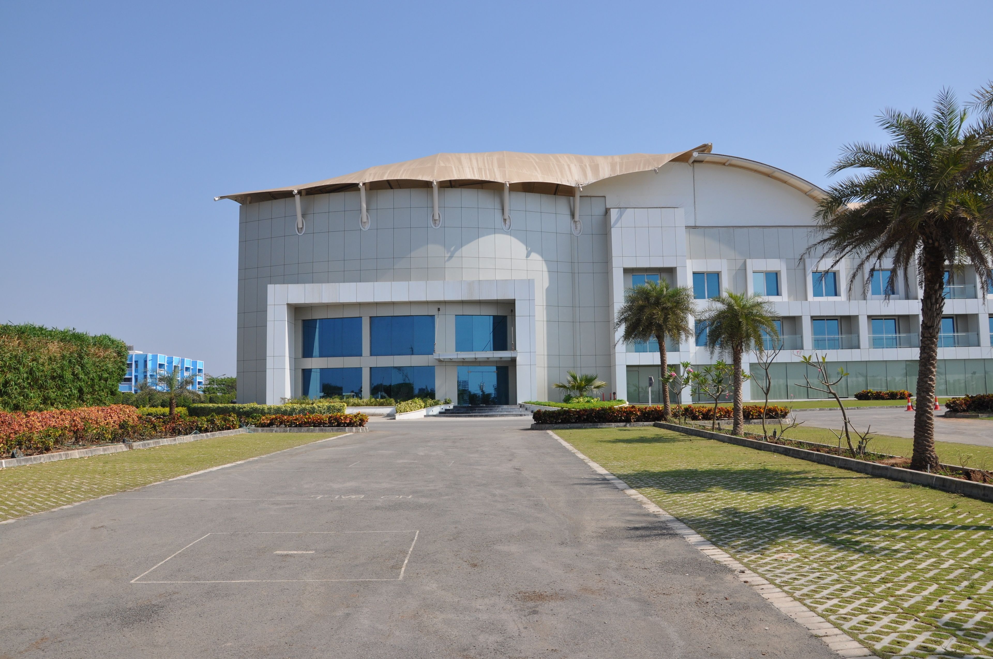 A modern building with a large entrance, surrounded by well-maintained landscaping and palm trees.