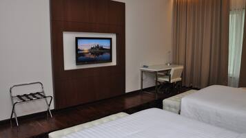A hotel room with two beds, a desk, a TV mounted on the wall, and a chair.