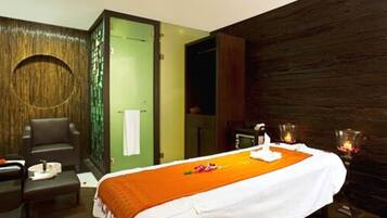 A spa room with a bed, a massage table, and a seating area.