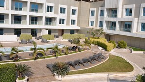 A modern hotel with a rooftop pool, lounge chairs, and well-maintained landscaping. - The Deltin Hotel (Daman)