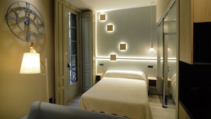 Una habitación de hotel con una cama, un reloj, una lámpara y un espejo.