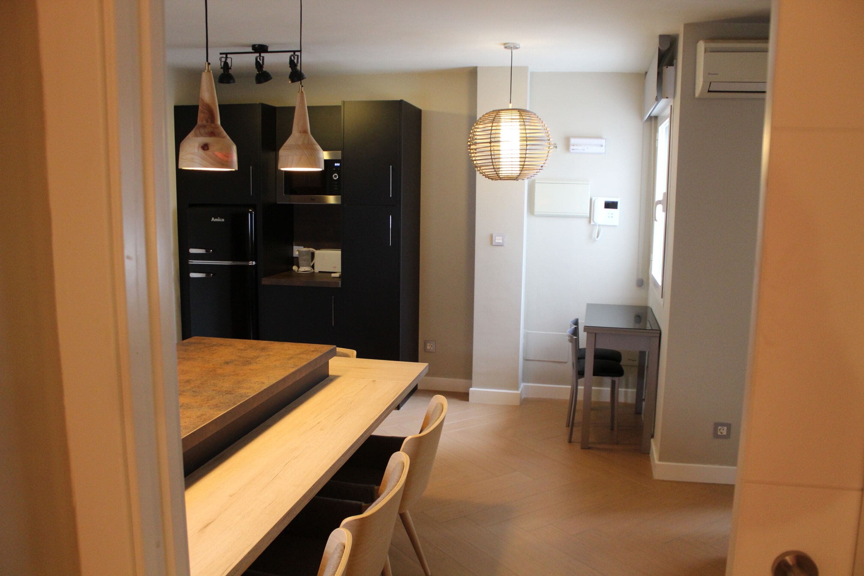 A modern kitchen with dark cabinets, a wooden countertop, and pendant lighting.