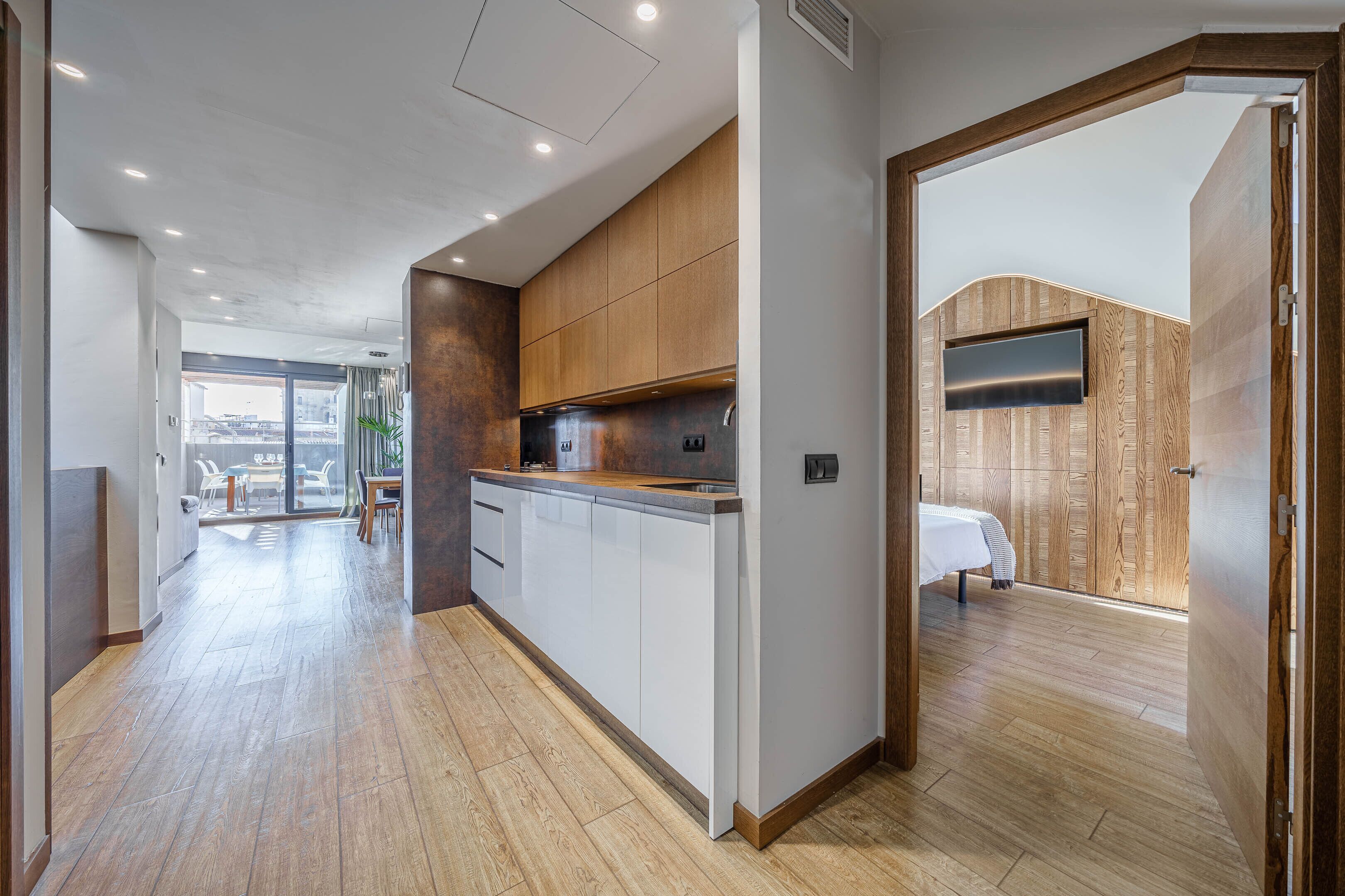 A modern kitchen with wooden cabinets, a built-in oven, and a large window.