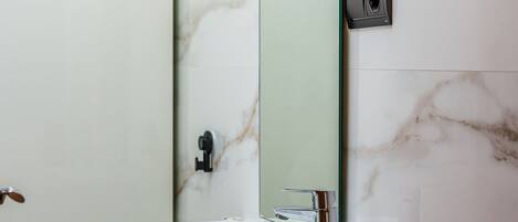 A bathroom with a white sink, a mirror, and a marble wall.