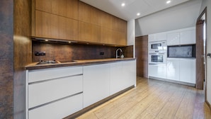 Una cocina moderna con armarios de madera, un lavamanos de acero inoxidable y electrodomésticos integrados, incluyendo un microondas y un horno.