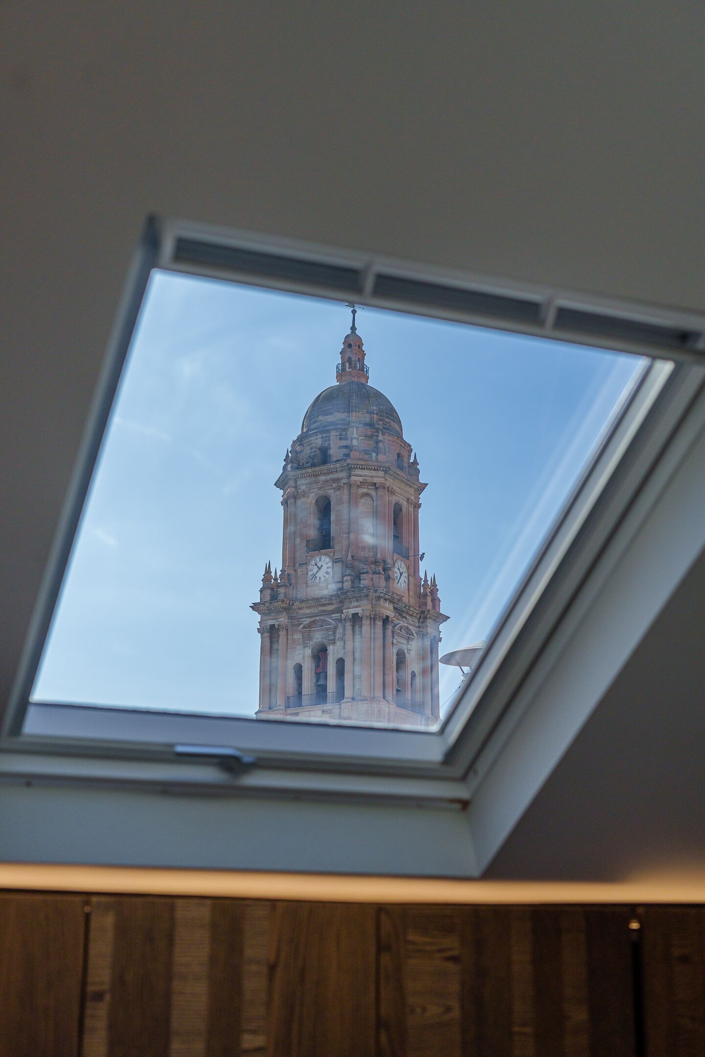 Une lucarne offrant une vue sur un bâtiment historique.