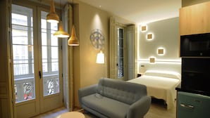 Una habitación de hotel moderna con sofá, cama, una mesita y refrigerador.