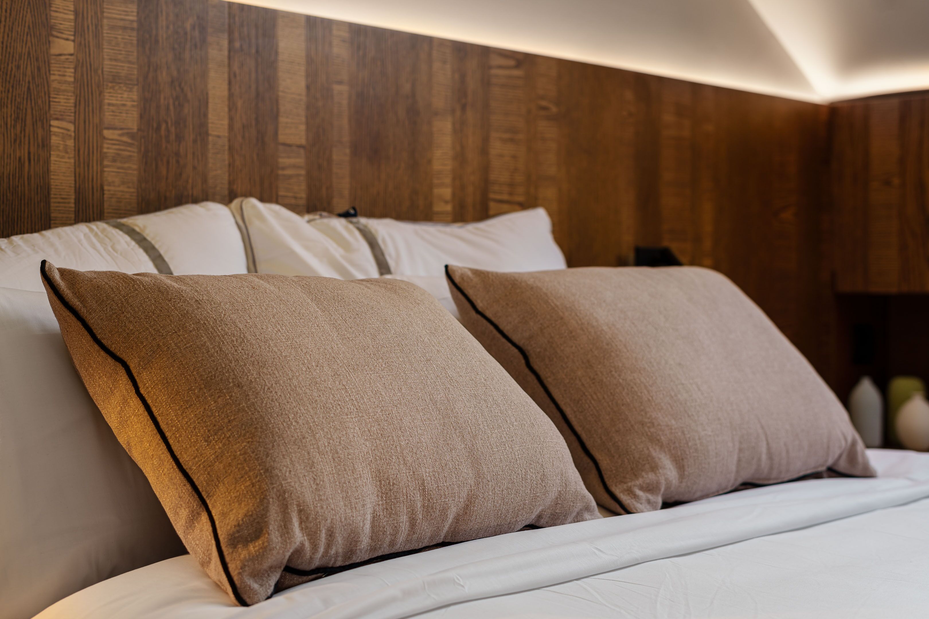 A bed with two pillows and a wooden headboard.