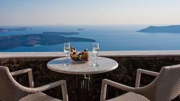 Un tavolo con due sedie e una ciotola di frutta, con vista su un panorama mozzafiato del mare e delle isole.