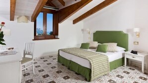 Une chambre à coucher comprenant un lit, une chaise, une table de chevet, une fenêtre et une vue sur les montagnes.
