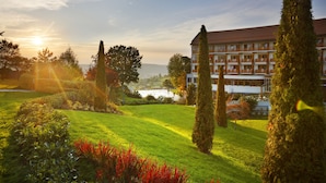 A hotel with a large building, manicured lawn, and tall trees. - Hotel & Spa Der Steirerhof Bad Waltersdorf (Bad Waltersdorf)