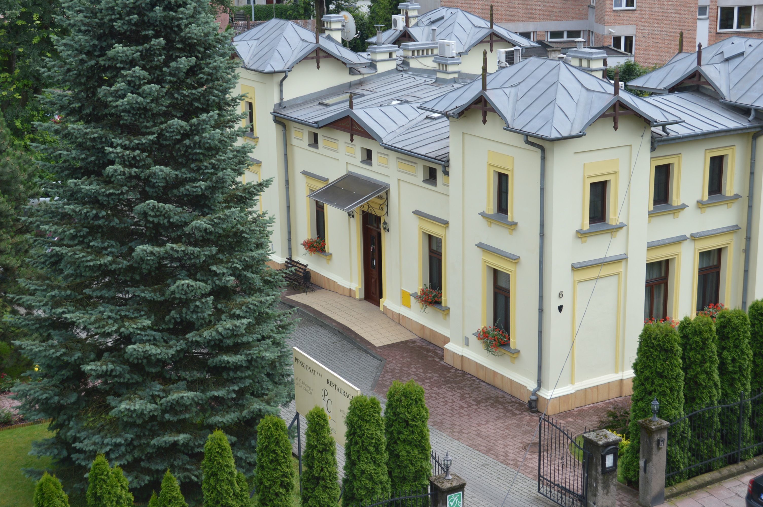 A multi-story building with a yellow facade, multiple windows, and a brick pathway leading to the entrance.