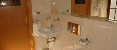Een badkamer met een wastafel, toilet en spiegel.