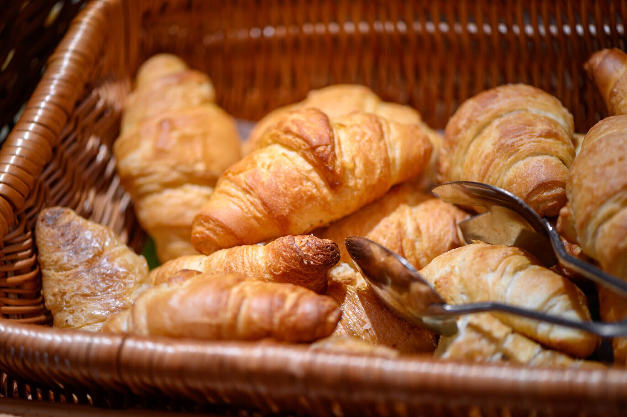 Un panier en osier rempli de croissants de différentes sortes.