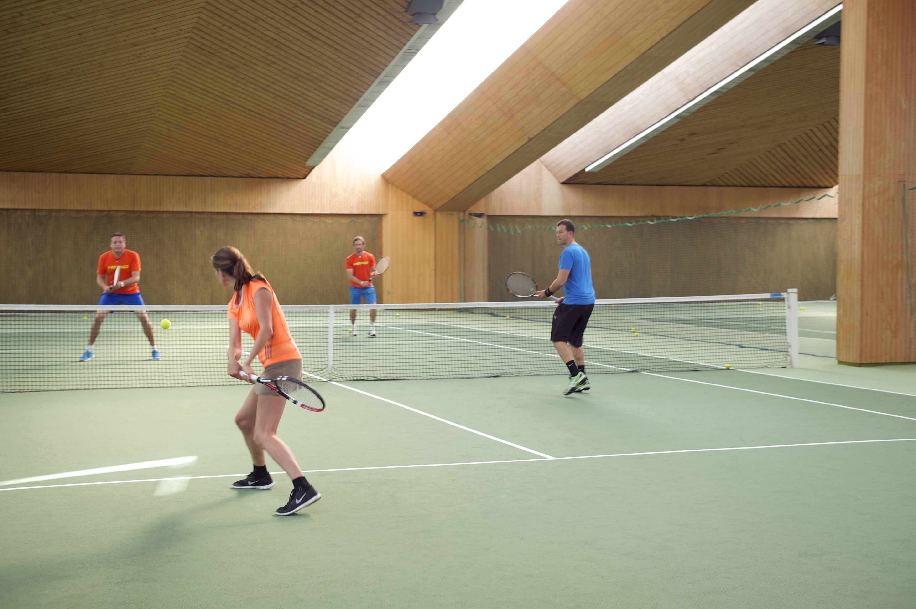 Ein Hallen-Tennisplatz mit Holzwänden und einem grünen Belag.