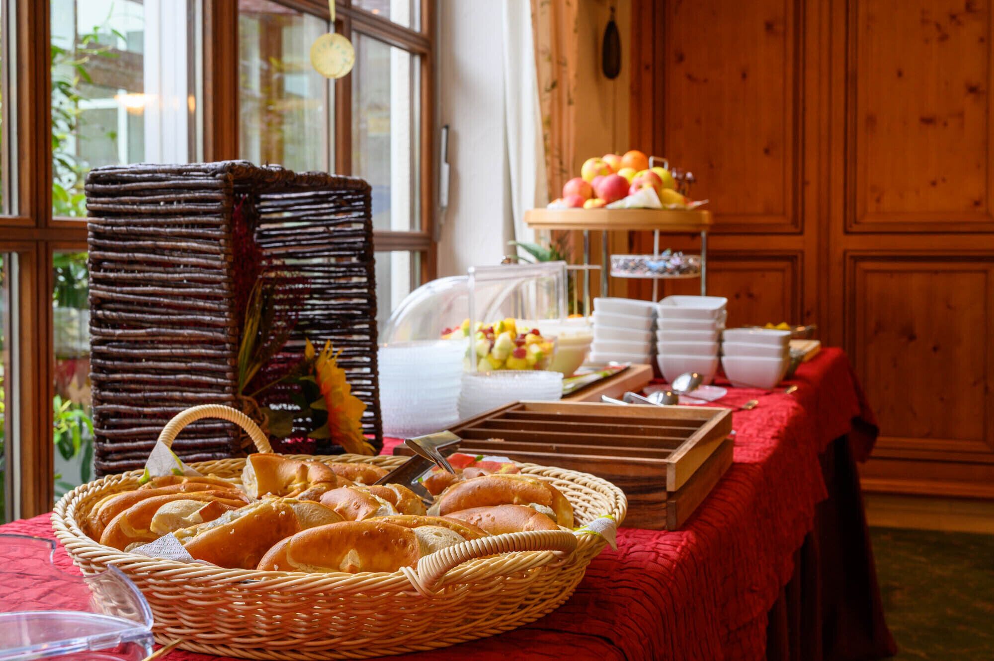 A breakfast buffet with bread, pastries, and fruit.