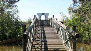 A wooden pedestrian bridge with a metal railing, surrounded by greenery and trees. - Marielyst Feriepark & Camping (Vaeggerlose)