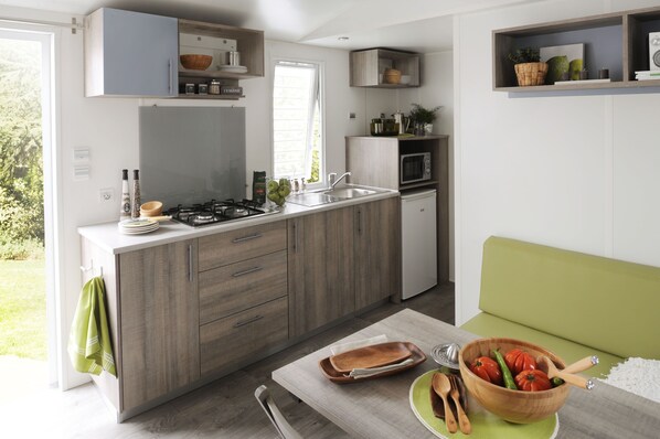 Une cuisine moderne dotée d’un îlot central, d’appareils électroménagers intégrés et d’un coin salon agrémenté de plantes.